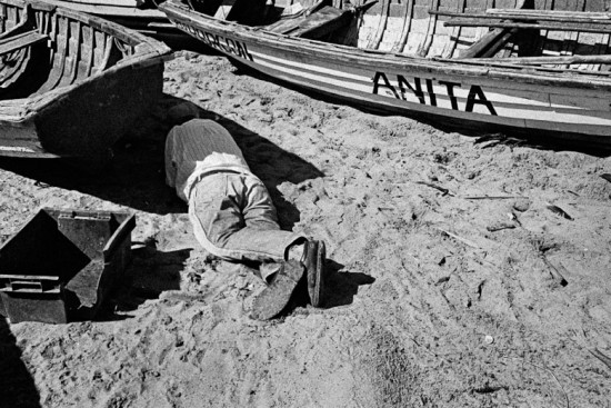A Chilean fisherman, after drinking a couple of pisco shots, rests in the shadow of his boat on the beach of Quintero, Chile, 19 April 2002.